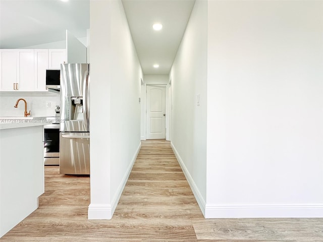 hallway featuring sink and light hardwood / wood-style flooring