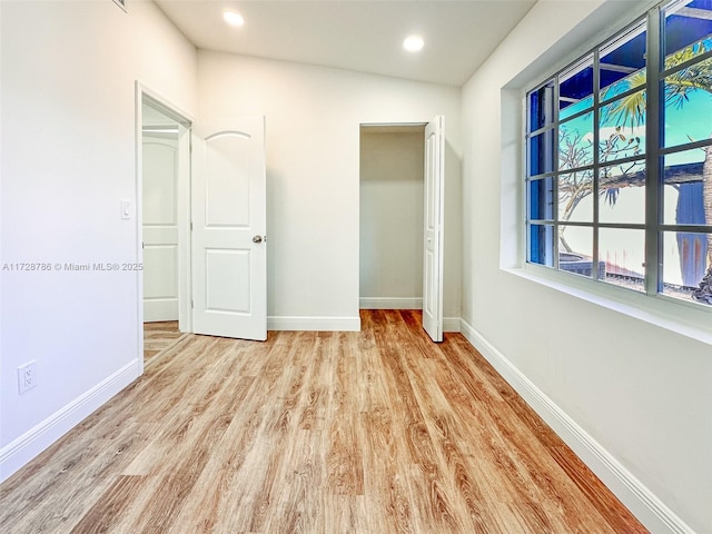 unfurnished bedroom featuring a closet, light hardwood / wood-style flooring, and lofted ceiling