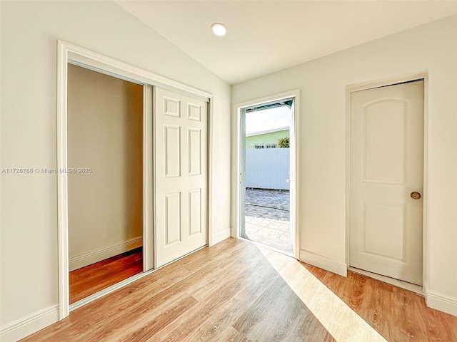 corridor with light hardwood / wood-style floors and vaulted ceiling