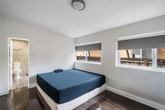 bedroom with dark wood-type flooring and connected bathroom