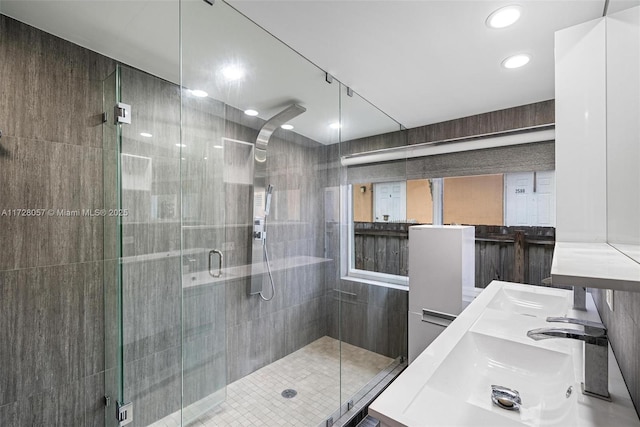 bathroom with a shower with shower door and sink