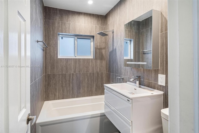 full bathroom featuring toilet, vanity, tile walls, decorative backsplash, and shower / bath combination