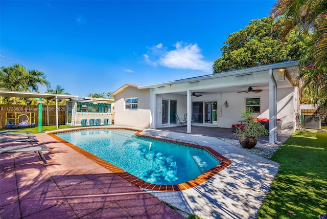 rear view of property featuring ceiling fan, a playground, and a patio