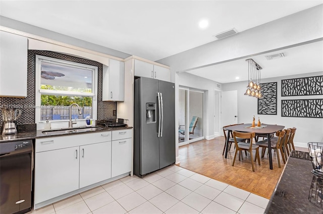 kitchen featuring white cabinetry, hanging light fixtures, black dishwasher, stainless steel fridge, and sink