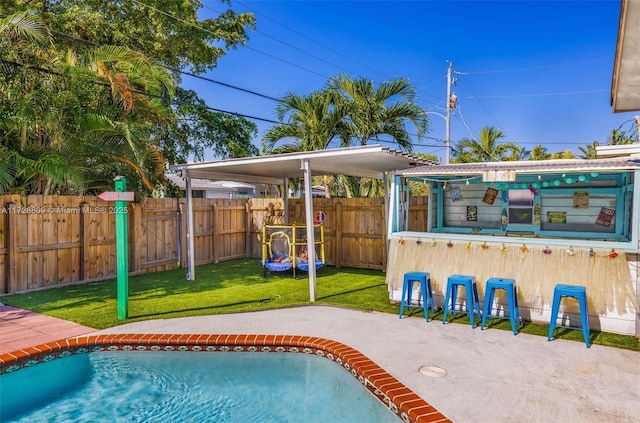 view of pool featuring a patio, a lawn, and a bar