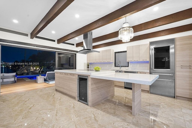 kitchen featuring island range hood, a spacious island, beverage cooler, pendant lighting, and a breakfast bar