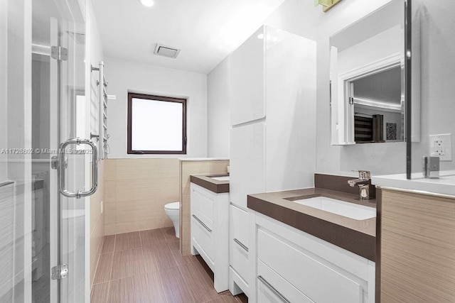 bathroom with a shower with shower door, toilet, and vanity