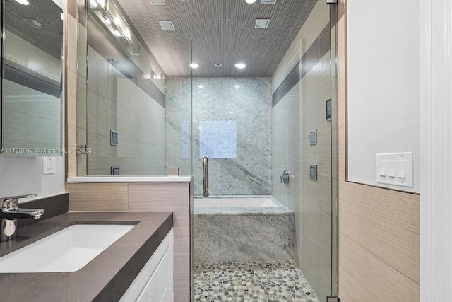 bathroom featuring tile walls, vanity, and plus walk in shower