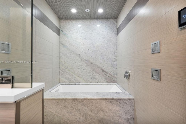 bathroom with tile walls and a relaxing tiled tub