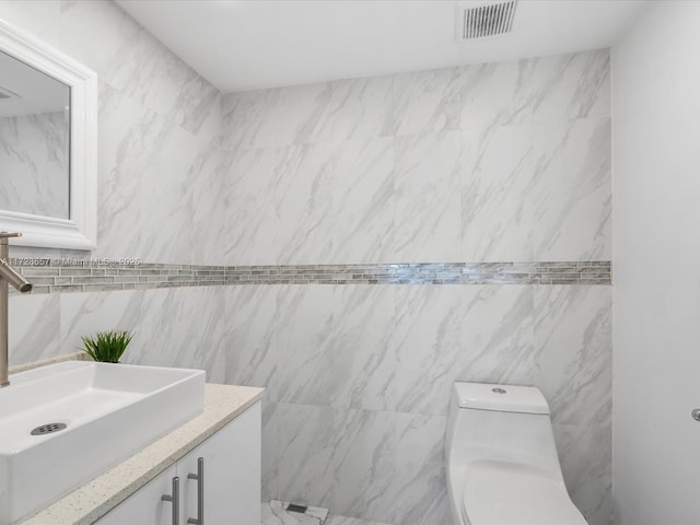 bathroom with toilet, tile walls, and vanity