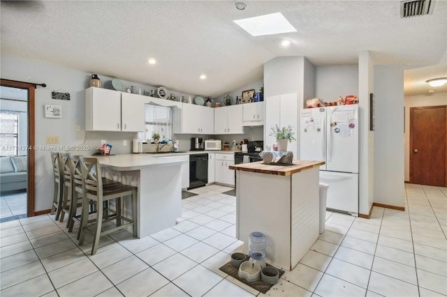 kitchen with lofted ceiling with skylight, a textured ceiling, white cabinets, a breakfast bar, and black appliances