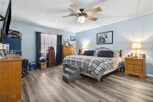 bedroom with a textured ceiling, ceiling fan, and wood-type flooring