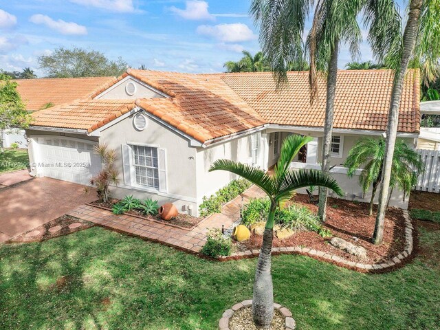 mediterranean / spanish-style home featuring a garage and a front yard