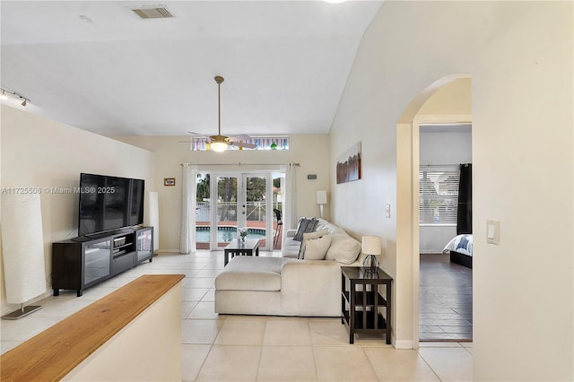 tiled living room featuring vaulted ceiling, french doors, and ceiling fan