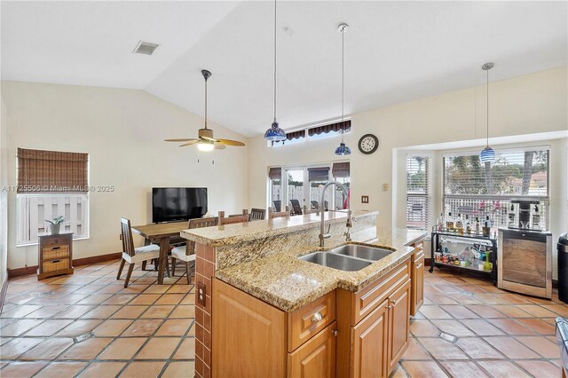 kitchen with a kitchen island with sink, sink, lofted ceiling, and hanging light fixtures