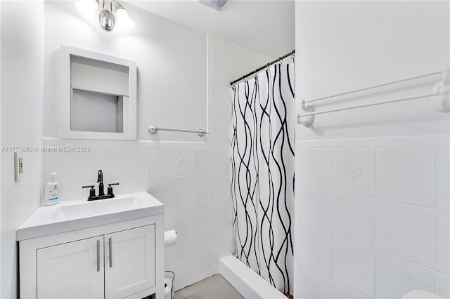 bathroom featuring walk in shower, vanity, and tile walls