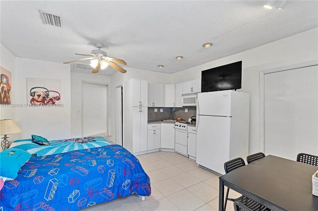 tiled bedroom with white refrigerator, ceiling fan, and a textured ceiling