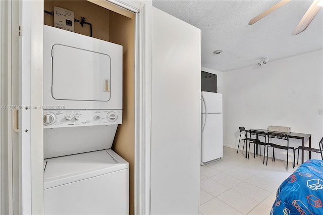 laundry room with light tile patterned flooring, ceiling fan, a textured ceiling, and stacked washer / drying machine