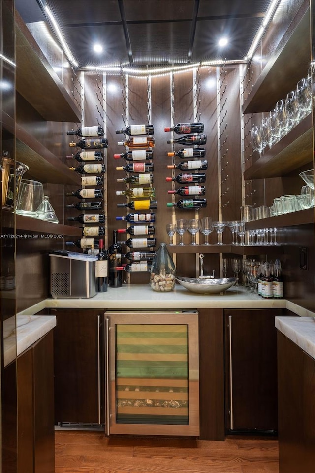 wine room featuring wood-type flooring, beverage cooler, and bar area