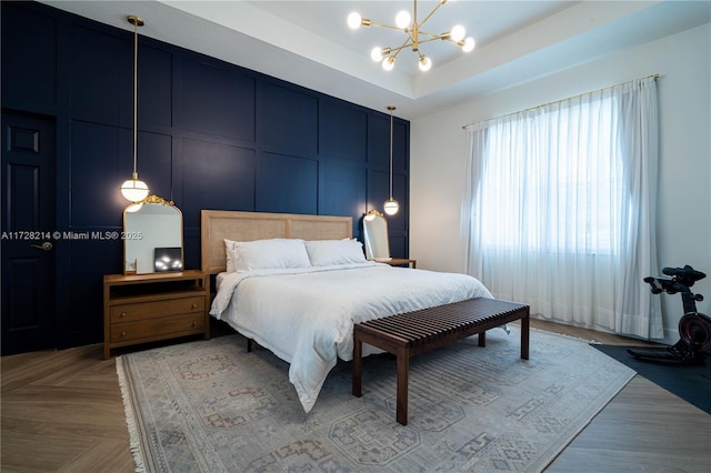 bedroom featuring a notable chandelier, a tray ceiling, and light parquet flooring