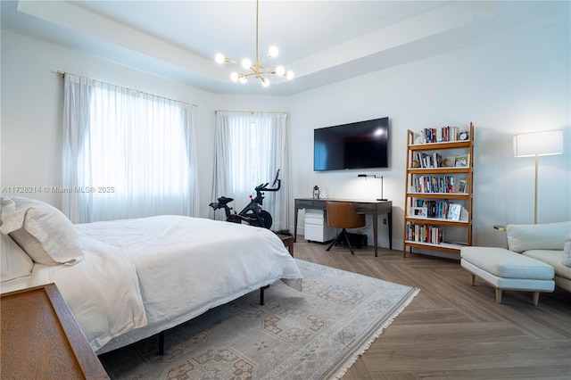 bedroom with parquet floors, a chandelier, and a tray ceiling