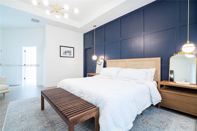 bedroom with light wood-type flooring and a notable chandelier