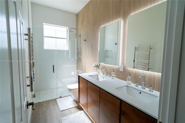 bathroom with toilet, a shower with shower door, wood-type flooring, vanity, and radiator