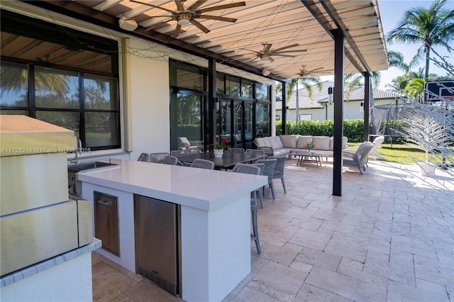 view of patio with an outdoor living space, a wet bar, ceiling fan, and exterior kitchen