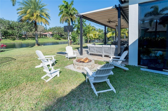 view of yard featuring ceiling fan, a patio, and an outdoor living space with a fire pit