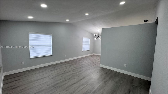 unfurnished room featuring lofted ceiling, dark hardwood / wood-style flooring, and an inviting chandelier