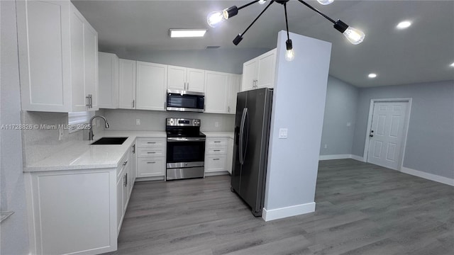 kitchen featuring sink, white cabinetry, stainless steel appliances, light stone counters, and light hardwood / wood-style floors