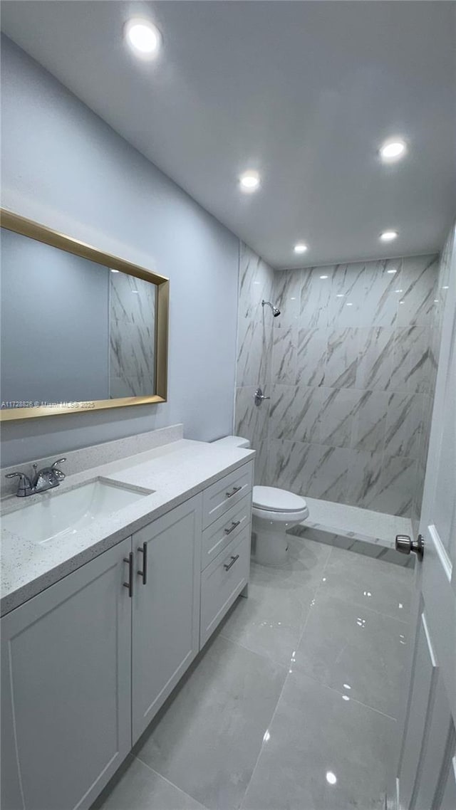 bathroom with vanity, tiled shower, and toilet