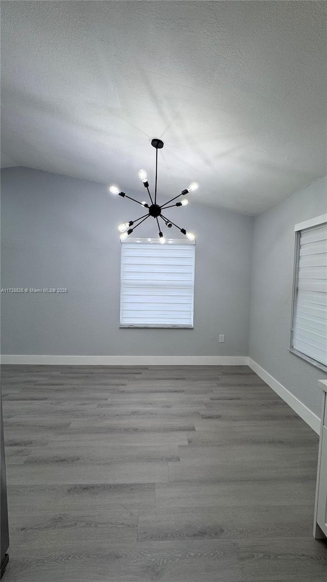 empty room featuring a chandelier and hardwood / wood-style floors