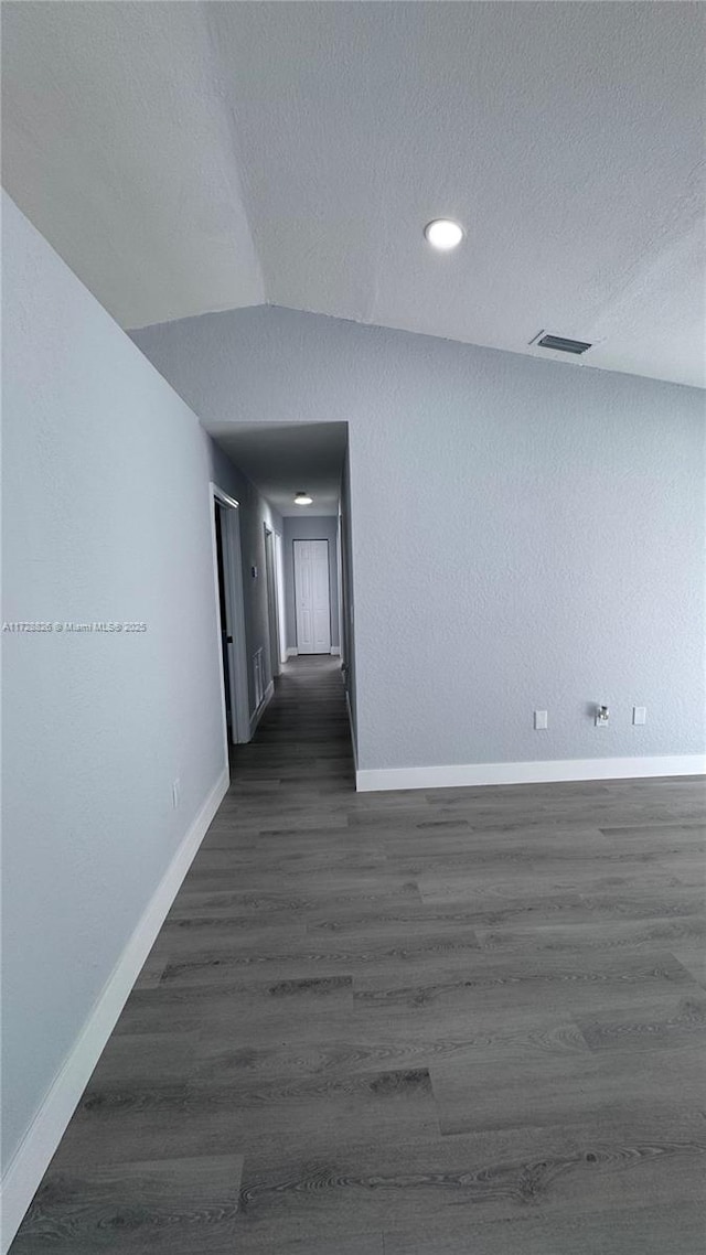 hall featuring lofted ceiling, dark hardwood / wood-style floors, and a textured ceiling