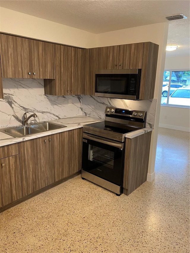 kitchen featuring a textured ceiling, stainless steel appliances, tasteful backsplash, and sink