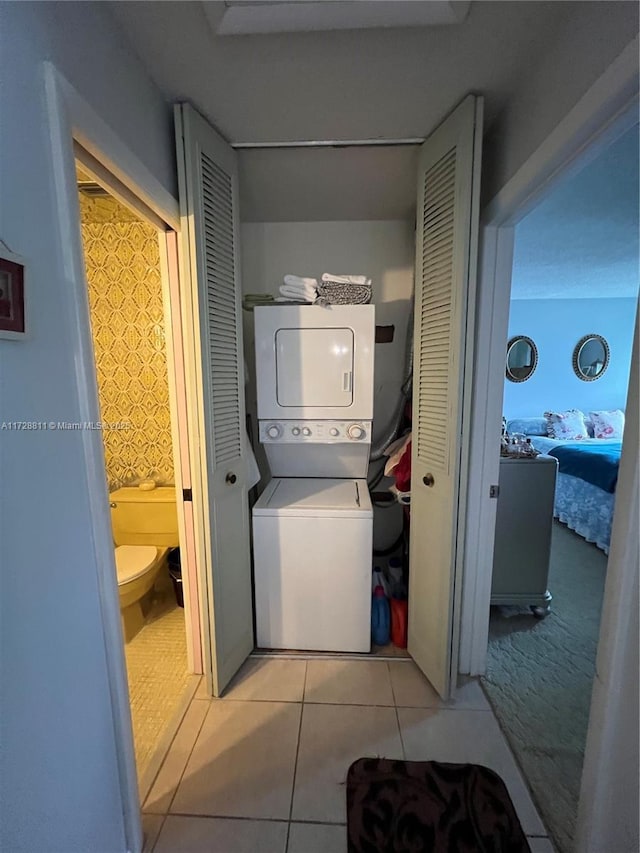 laundry room featuring light tile patterned floors and stacked washing maching and dryer