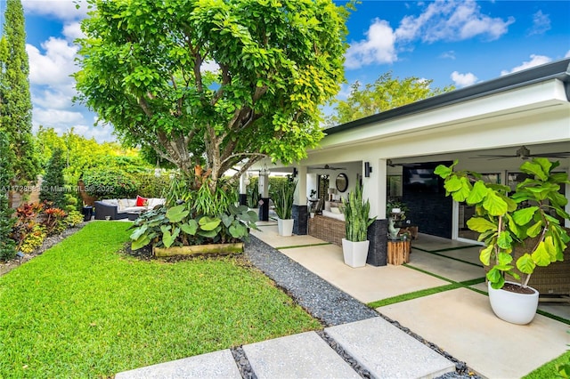 view of yard featuring ceiling fan, an outdoor living space, and a patio