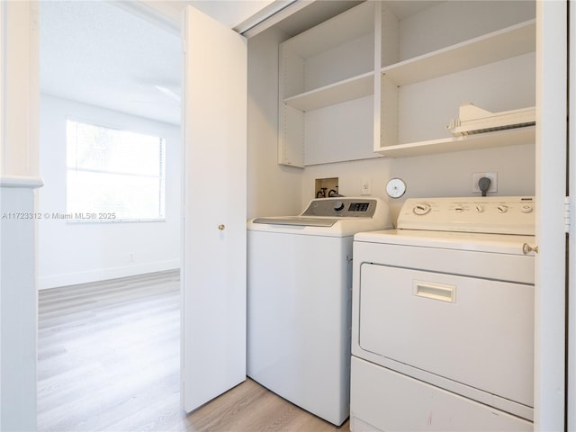 laundry area featuring washing machine and dryer and light hardwood / wood-style floors