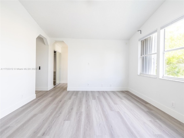 spare room with light wood-type flooring and vaulted ceiling