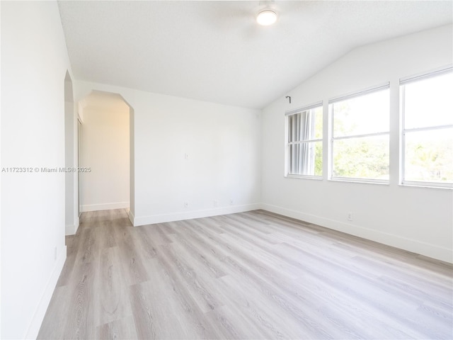 spare room featuring light hardwood / wood-style flooring and vaulted ceiling