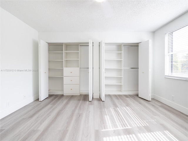 unfurnished bedroom with multiple closets, a textured ceiling, and light hardwood / wood-style floors