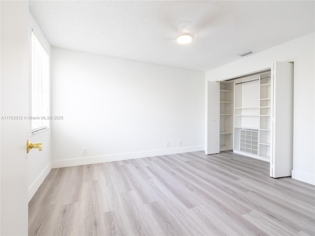 unfurnished bedroom with a closet, a textured ceiling, and light hardwood / wood-style flooring