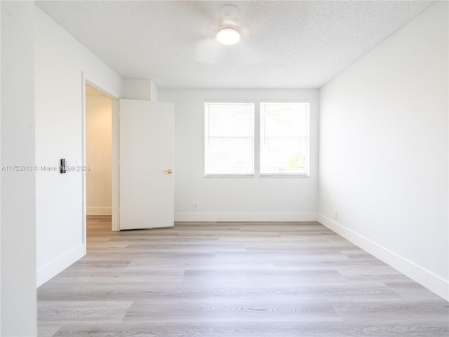 unfurnished room with light wood-type flooring and a textured ceiling