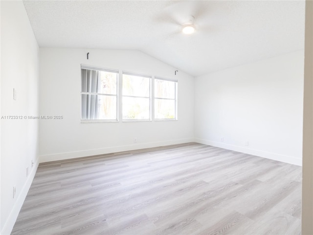 unfurnished room featuring lofted ceiling, a textured ceiling, and light hardwood / wood-style flooring