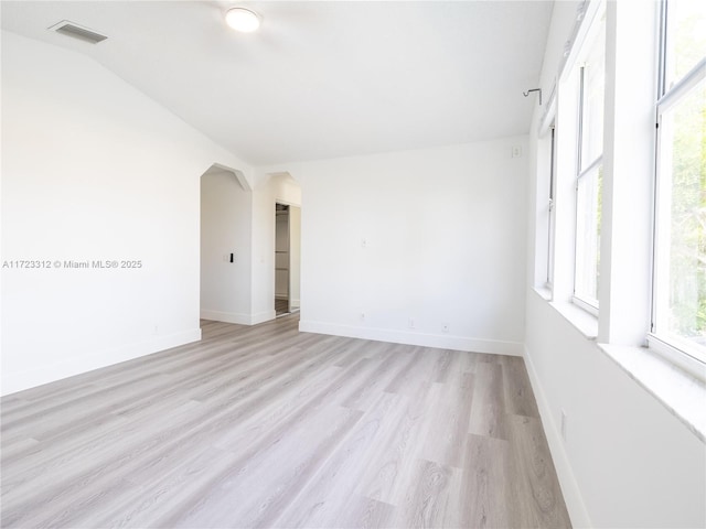 spare room with light hardwood / wood-style flooring and vaulted ceiling