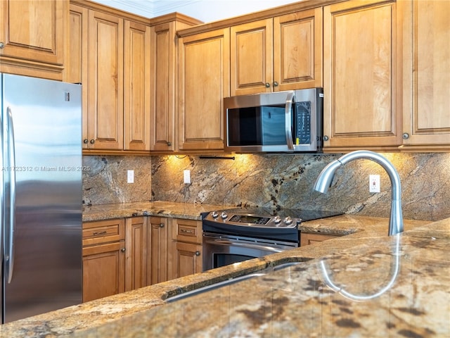 kitchen with tasteful backsplash, appliances with stainless steel finishes, stone counters, and ornamental molding