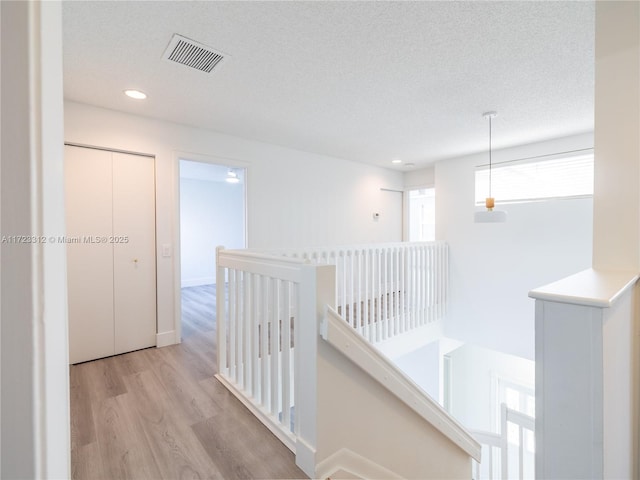 corridor featuring a textured ceiling and light hardwood / wood-style floors