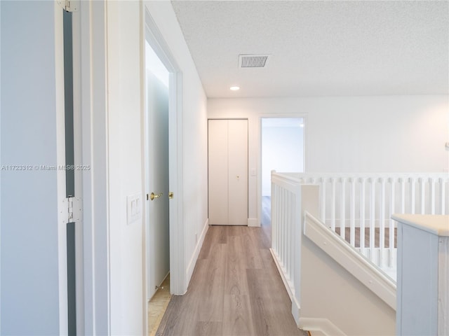 hallway featuring a textured ceiling and light hardwood / wood-style floors