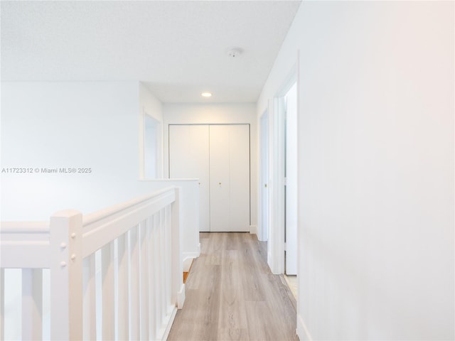 corridor featuring a textured ceiling and light hardwood / wood-style flooring