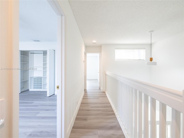 corridor with wood-type flooring and a textured ceiling